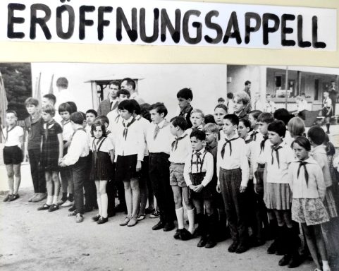 Gruppierung von Kindern in uniformen, die bei einer Eröffnungszeremonie stehen.