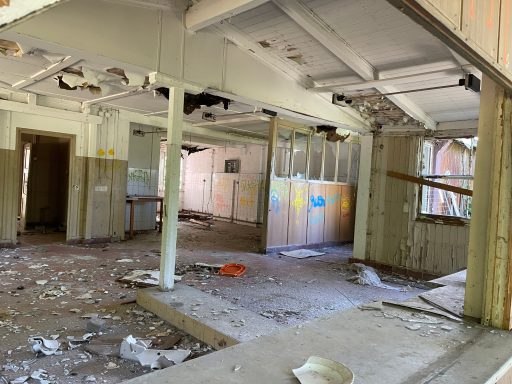 Verlassene, verwahrloste Innenräume mit beschädigten Wänden und debris auf dem Boden.